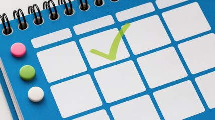 Leinwandbilder - A blue spiral calendar with a checkmark indicating a completed task, accompanied by colorful markers.
