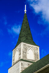 Wall Mural - A church steeple with a green roof and a white cross on top