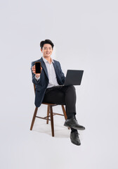 Wall Mural - Full body image of young Asian business man using phone and laptop ,sitting in chair on white background