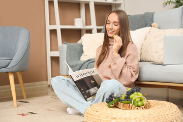 Wall Mural - Young woman with grapes reading magazine on floor at home