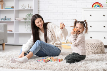 Cute little girl with teacher and cubes learning alphabet on carpet at home