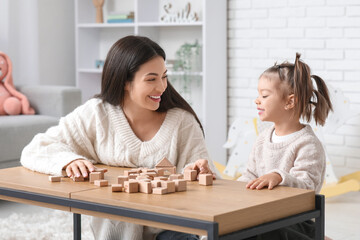 Wall Mural - Cute little girl with teacher and cubes learning alphabet at table in room