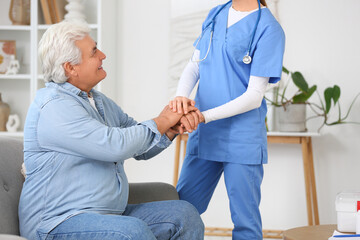 Wall Mural - Female doctor with mature man holding hands at home