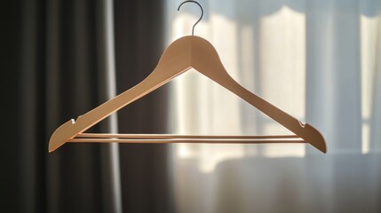 Aufkleber - Wooden clothes hanger with minimalist design hanging in soft natural light against a blurred background of curtains and window.