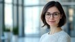 © The 2R Artificiality - Charming dark-haired business woman wearing glasses confidently conversing on mobile phone in modern spacious office with soft natural light and large empty copyspace for text
