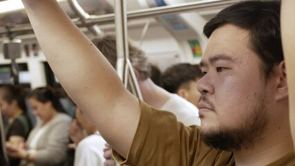 Canvas Print - view inside public transportation train commuter while an asian man holding looped handle handrails traveling with subway.urban interior of a city subway train with some passengers.