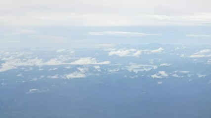 Wall Mural - aerial view over cloudscape from airplane flying with thick fog and cloud above the beautiful green natural forest with river in rainy day.