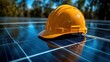 © Erisna Yolanda - Yellow hard hat rests on solar panel array outdoors.