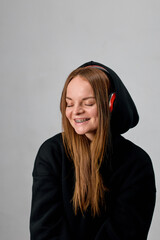 Portrait of a charming woman with braces wearing a black hoodie with headphones