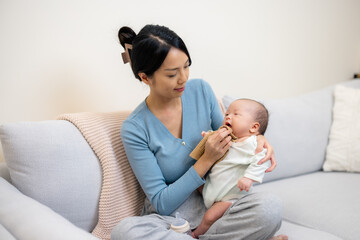 Canvas Print - Mother assisting baby to clean mouth on sofa