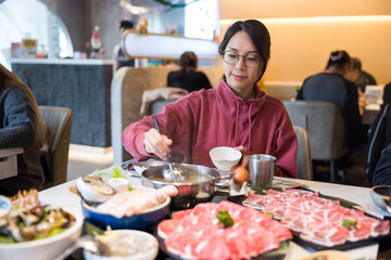 Wall Mural - Asian woman eating hotpot with beef slices