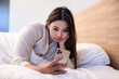 © SHUTTER DIN - woman feel uncomfortable and stressed when she saw a message on her phone while lying on a bed in bedroom inside an apartment.