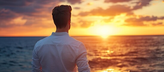 Poster - A brunette man stands with his back to a seascape during sunrise Concept copy space for advertising on the back
