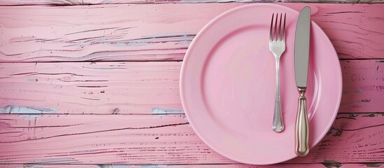 Fototapete - Empty plate accompanied by a fork and knife Pink wooden backdrop featuring the plate silver fork and knife with copy space above in a top view perspective
