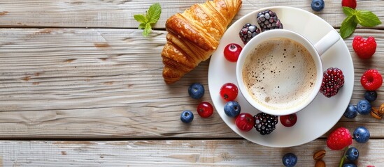 Poster - Breakfast idea featuring a coffee cup croissants cream and fresh berries Set against a light wooden background top view copyspace