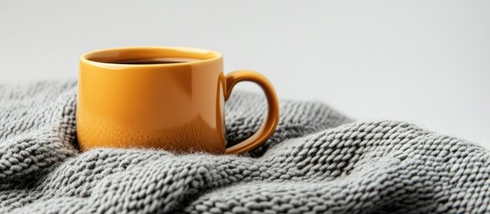 Wall Mural - Coffee mug resting on a gray wool scarf against a white background with copy space