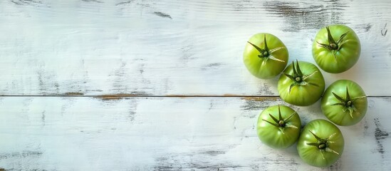 Fototapete - Green unripe tomatoes on a white wooden surface Top view. with copy space image. Place for adding text or design