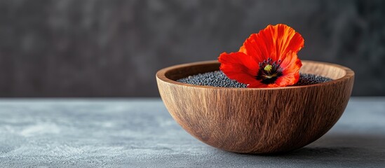 Poster - Wooden bowl containing poppy seeds and a flower on a grey table room for text. with copy space image. Place for adding text or design