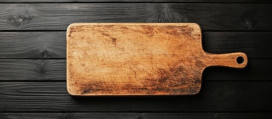 Poster - Top view of a small empty cutting board on a black wooden table with copyspace
