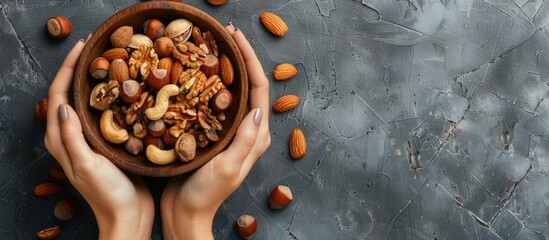 Aufkleber - Woman s hands holding a wooden bowl filled with mixed nuts Healthy food and snack option Vegan vegetarian raw meal idea Walnuts almonds hazelnuts Top view. with copy space image