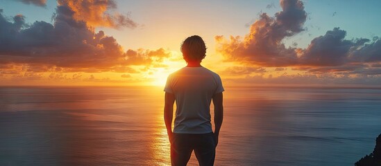 Poster - A brunette man stands with his back to a seascape during sunrise Concept copy space for advertising on the back