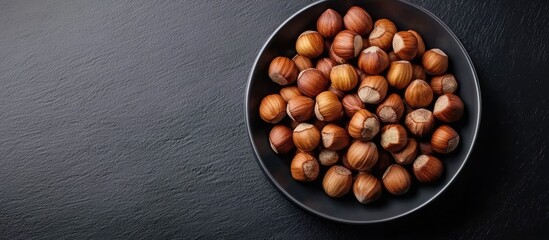 Aufkleber - Top view of hazelnuts on a plate against a black background A nutritious and calorie dense snack. with copy space image. Place for adding text or design