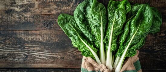 Aufkleber - Swiss chard leaves on a wooden table featuring multiple green leaves with white stalks in a colored bag. with copy space image. Place for adding text or design