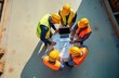 © miss irine - Construction site team gathers around laptop, blueprints. Engineers review project plans. Teamwork, discussion happen at workplace. Professionals in safety vests, hard hats. Project progress, site