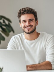 Poster - cheerful young man smiling at computer in modern workspace with soft natural light, neutral backgrou
