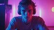 © The 2R Artificiality - Young man with headphones focused on gaming in a dimly lit room with neon pink and blue lights showcasing intense expression, plenty of copyspace for text