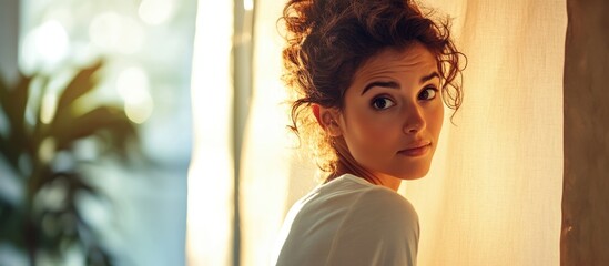 Poster - gorgeous woman with curly hair sitting by window in warm natural light creating inviting atmosphere 