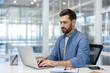 © Liubomir - Serious and focused man typing on laptop keyboard. Businessman in casual clothes working inside office at workplace.