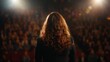 © Evon J - Caucasian female speaker facing audience in theater with stage lights