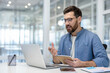 © Liubomir - Man at workplace watching training video course webinar, office worker writing training data in notebook, businessman serious inside office at workplace Clarifies information on the video call.