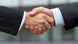 © Iona - A close-up view of a handshake between business partners symbolizes agreement, trust, and successful collaboration against a blurred urban backdrop.