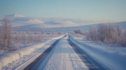 Poster - Tire tracks on a snow-covered road winding through a serene winter landscape with mountains in the background and a clear blue sky.