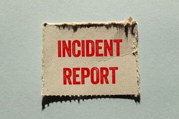 Incident report message written on ripped torn paper piece on gray background. Conceptual incident report symbol. Copy space.
