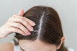 © KMPZZZ - Damaged hair symptom, problem hair fall asian young woman, girl worry about balding, looking at scalp in mirror, hand in break into front hair loss, thin problem. Health care treatment for beauty.