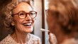 © Aleksandar - An elderly woman with glasses smiles brightly while looking at herself in a bathroom mirror, celebrating wisdom and happiness, in a cozy, intimate setting.