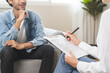 © KMPZZZ - Psychology, depression. Happy smile asian young man patient mental therapy explain symptom with psychologist while doctor woman taking notes at clinic. Psychologist with sick mental health person.