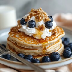 Wall Mural - Delicious stack of fluffy pancakes topped with whipped cream, blueberries, and walnuts drizzled with syrup on a rustic table setting