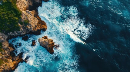 Poster - Aerial view of ocean waves breaking against rugged coastal rocks with clear space for text placement and vibrant water colors