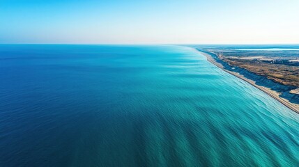 Poster - Aerial view of tranquil blue ocean waves meeting the shore under a clear sky showcasing nature's serene beauty and coastline.