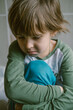 © leroy - Little boy toddler is sitting alone on the floor and hugging his knees after suffering an act of bullying.