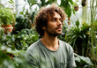 © Hanna - Man enjoys tranquility in a lush greenhouse surrounded by a variety of tropical plants in bright natural light