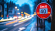 © Infinity Lens - Sign on the side of the city street in the evening with text 'limit cars passing by blurred in motion. prohibited driving behavior restriction, restriction plate, speed regulation, town traffic.