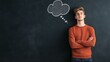 © olga_demina - Young man stands with crossed arms against a dark chalkboard, contemplating a chalk drawn thought bubble above him, symbolizing questioning, messaging, and the process of generating ideas