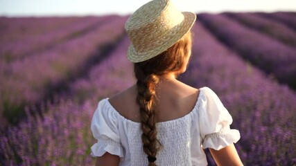 Wall Mural - Girl is runs through a field of purple flowers. She is wearing a white shirt and a hat.