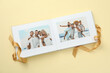 © New Africa - Open photo album with photos and ribbon on beige background, top view
