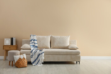 Poster - Comfortable sofa with pillows, blanket, pouf and bag indoors, space for text